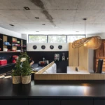 Open-plan custom kitchen with black island, timber cabinetry, integrated dining seating, and bespoke joinery.