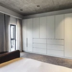 Modern custom bedroom joinery with floor-to-ceiling built-in wardrobes, integrated drawers, and minimalist white cabinetry.