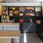 Custom kitchen joinery with timber shelving, black cabinetry, built-in dining seating, and open-plan contemporary design.