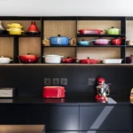 Custom kitchen joinery with timber shelving, black cabinetry, built-in dining seating, and open-plan contemporary design.