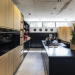 Luxury custom kitchen with black island, timber cabinetry, integrated appliances, and bespoke joinery.